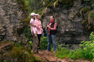 woman backpacker communicates with two teenage girls among the rocks in a natural landscape