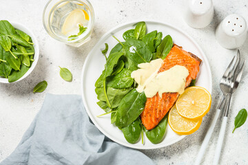 Salmon fillet with spinach and mustard yogurt dressing. Healthy food, keto diet. Top view at white table.