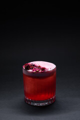 clover club cocktail drink with raspberry and rose petal on black background