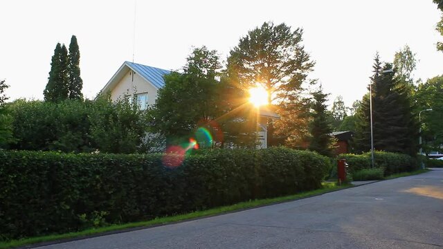 The sunshine, through the trees, falls around a residential house.