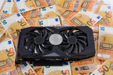 game video card on a pile of euro banknotes and bitcoin sign. cryptocurrency mining concept.