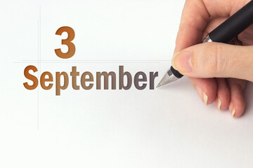 September 3rd. Day 3 of month, Calendar date. The hand holds a black pen and writes the calendar date. Autumn month, day of the year concept.