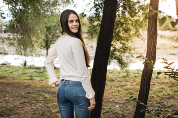 Mujer joven de espaldas y sonriendo con jeans ajustados