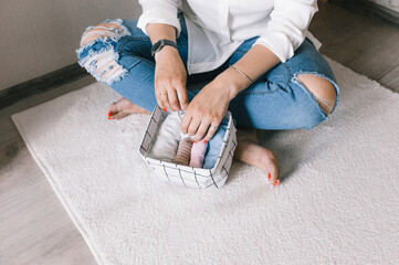 close-up of women's hands beautifully folding things into containers and boxes. The concept of proper storage of accessories and underwear in the closet