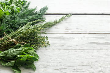 Empty space for text. Greens. Cilantro, dill, thyme, rosemary on a white boardwalk table.
