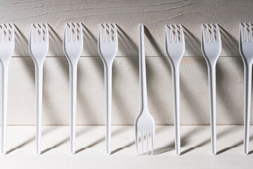 a row of forks standing against the wall, one of them upside down and different from the others