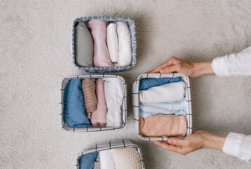 a neat housewife puts things in a laundry container during general cleaning with the help of a modern storage system. Top view The concept of a beautiful and comfortable organization