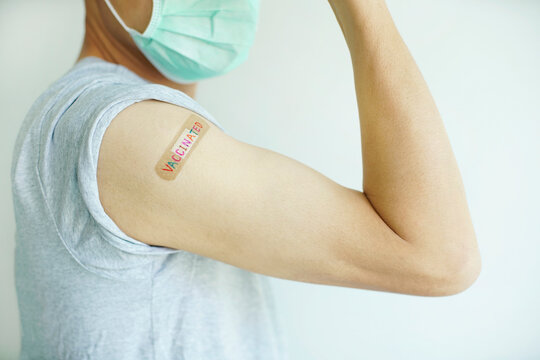A man raise his arm showing get vaccinated with multicolor ' VACCINATED ' write on wound plaster                                                              