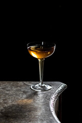 whiskey whisky cocktail in hollow stem coupe champagne glass on wood table with black backdrop