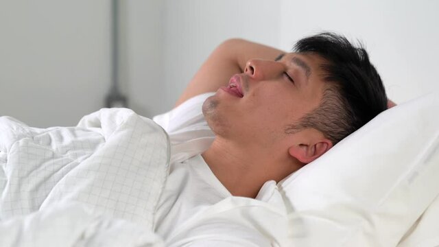 Young Asian man snoring While sleeping in bed.