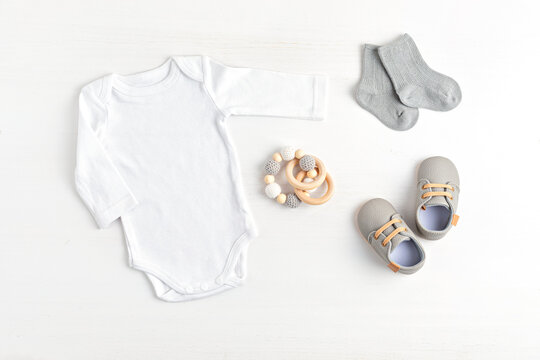 Mockup of white infant bodysuit made of organic cotton with eco friendly baby accessories. Onesie template for brand, logo, advertising. Flat lay, top view