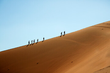 Fototapeta na wymiar People climbing sand dunes beside Deadvlei near Sossusvlei Namib-Naukluft National Park Namibia Africa
