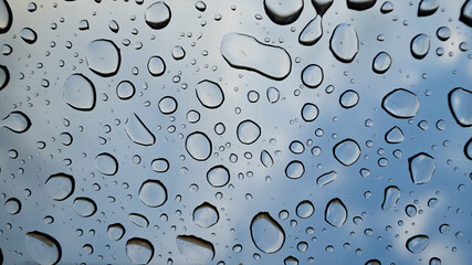 Regentropfen auf Glas bei blauem Himmel