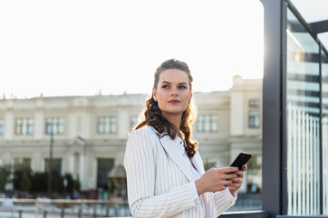 An attractive young woman walking in the city center, texting and laughing.
