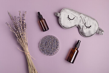 Sleeping mask and lavender essencial oil over purple background. Natural treatment of insomnia, relaxation, anti stress, quality of sleep concept. Flat lay, top view