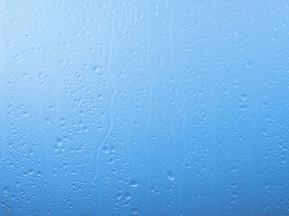 Raindrops on glass window over grey and blue sky