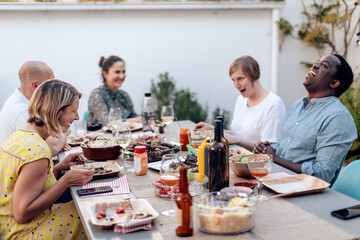 Multiracial friends eating and cheering together outdoor at terrace - Focus on left woman face