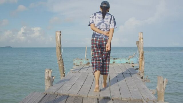Female Tourist walk relax along wooden bridge forword to sea