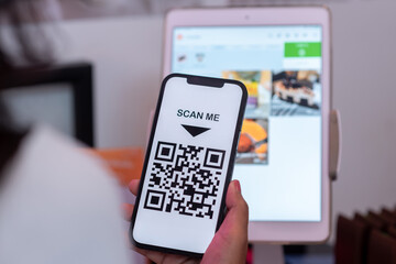 People's hands are using smartphones to scan QR codes.