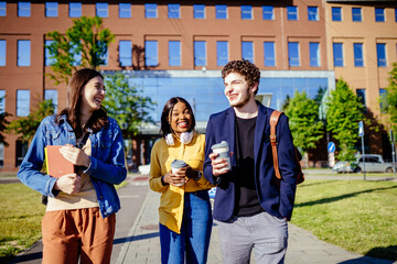 Mixed raced group of friends millennial students commuting in city. Three young people walking in the city street having fun.
