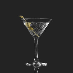 Alcoholic drink. Crystal goblet with clear alcohol and olive isolated on black background.