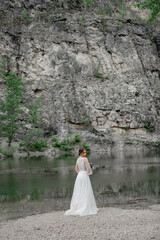 The bride in a white wedding dress on the bank of a mountain river.