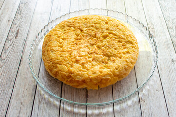 great thick potato omelette with onion on a transparent crystal tray served in a Spanish tapas bar