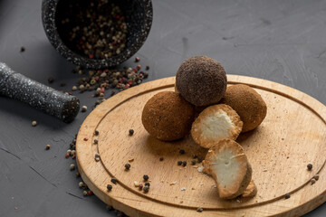 spicy cheese covered with round type spices on a wooden surface