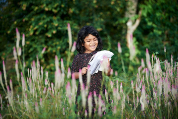 Asian schoolgirl reading a book and playing alone at natural park