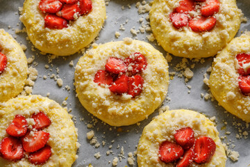Raw yeast sweet buns filled with strawberries sprinkled with butter crumble, prepared to baking. Homemade dessert