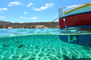 Sea level and underwater split photo of traditional wooden fishing boat anchored in Aegean island port with emerald crystal clear sea
