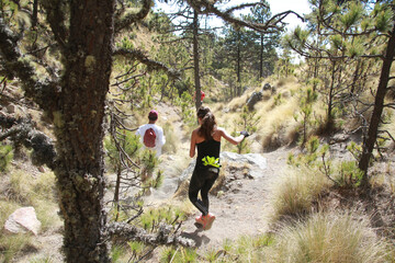 Young fitness woman and boyfriend trail running in a mountain path working out in nature on a beautiful day