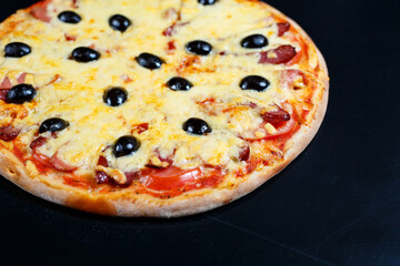 Pizza with cheese tomato sauce, olives, fresh mozzarella, parmesan and basil and meat on a dark background