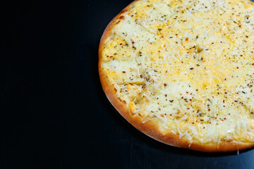 Delicious Four Cheeses pizza with cheddar, parmesan, mozzarella and tomato sauce on a black background. View from above.