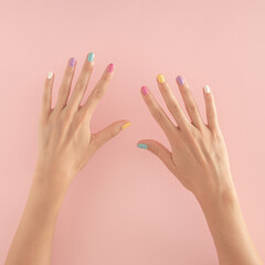 women hands with colorful nails on the pastel pink background. copy space.  summer modern tropical abstract art with female hand. minimal background idea with number ten