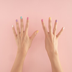 women hands with colorful nails on the pastel pink background. copy space.  summer modern tropical abstract art with female hand. minimal background idea with number nine