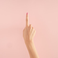 women hands with colorful nails on the pastel pink background. copy space.  summer modern tropical abstract art with female hand. minimal background idea with number one