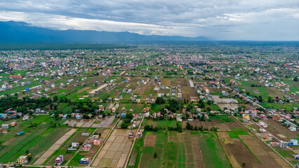 Aerial shot of houses scattered across a large farmland in the countryside Nepal.