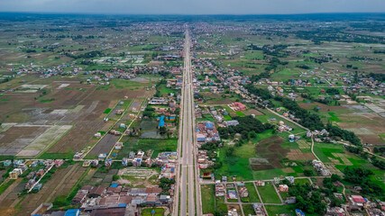 Aerial view of six-lane highway passing through meadows, fields and scattered houses towards...
