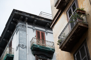 Fototapeta na wymiar Narrow street with small home balconies in Naples Italy. Flowers growing on beautiful old balconies . Balconies under the roof