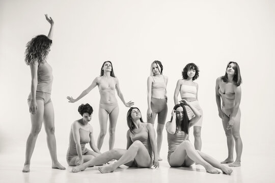 Women without makeup in beige clothes. Black and white photo with a group of girls on a light background. Girls with natural beauty. A group of women in one photo are standing in their underwear. 