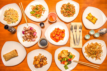 Top view image of a set of popular dishes offered in a Chinese restaurant. Sweet and sour pork, sautéed noodles, spring roll, chicken with almonds, three delights rice