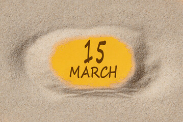March 15. 15th day of the month, calendar date. Hole in sand. Yellow background is visible through hole. Spring month, day of the year concept