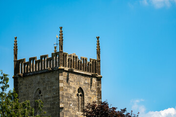 Ancient church spire and trees captured against bright blue sky