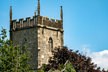 Ancient church spire and trees captured against bright blue sky