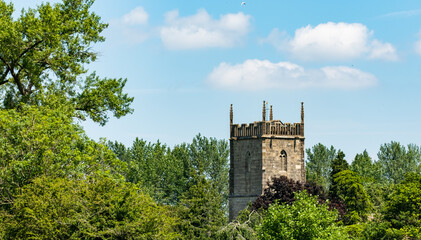 Fototapeta na wymiar Ancient church spire and trees captured against bright blue sky