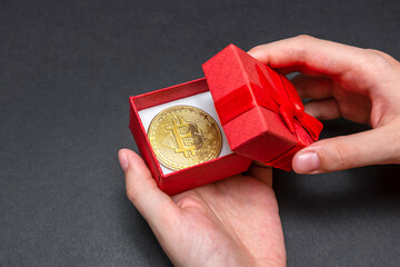 Bitcoin coin in a red gift box. christmas and new year gift. Hands open gift box with bitcoin coin, banner.