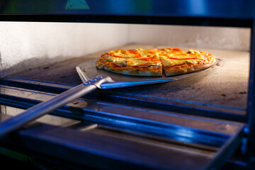Hot tasty American pizza with tomato cheese and meat with a thick crust on a metal shovel, the...
