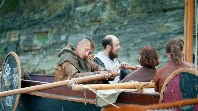 Vikings Sail on an Old Ship with a Lowered Sail on a Quiet River