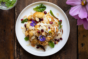 Roast cauliflower with almond flakes, pomegranate and tahini sauce